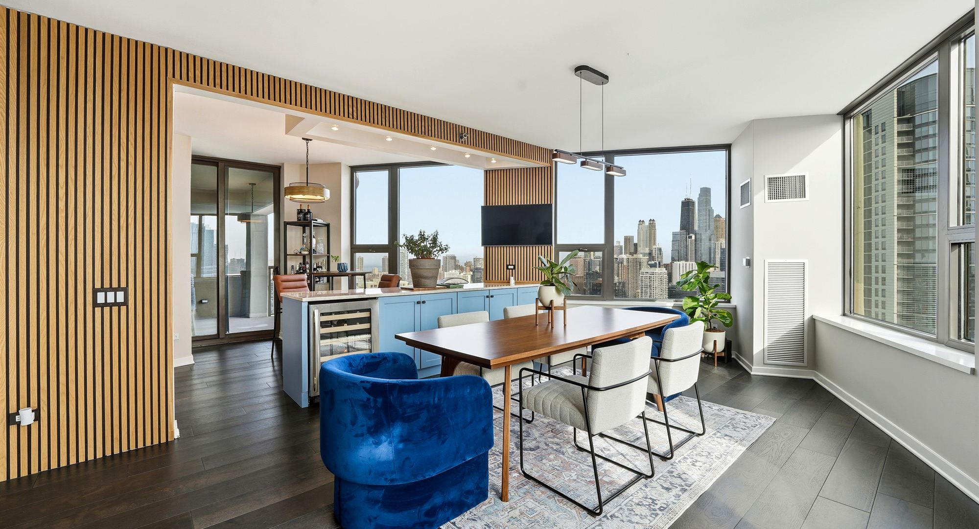 Finished high-rise residence with white-oak slat wall, custom island and Chicago skyline beyond