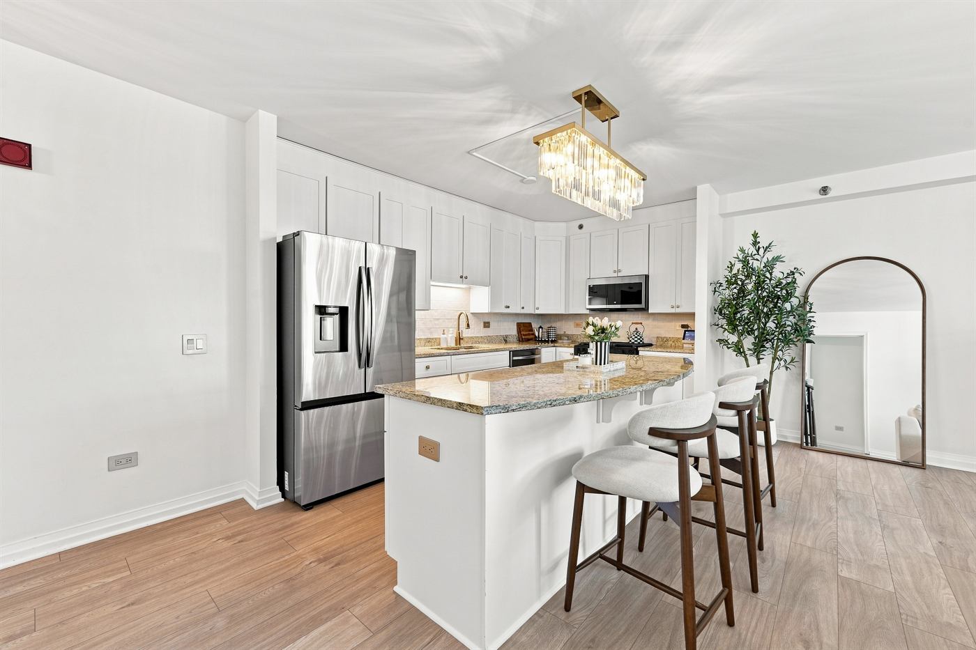 White shaker kitchen with granite island, brass linear pendant and white oak floors