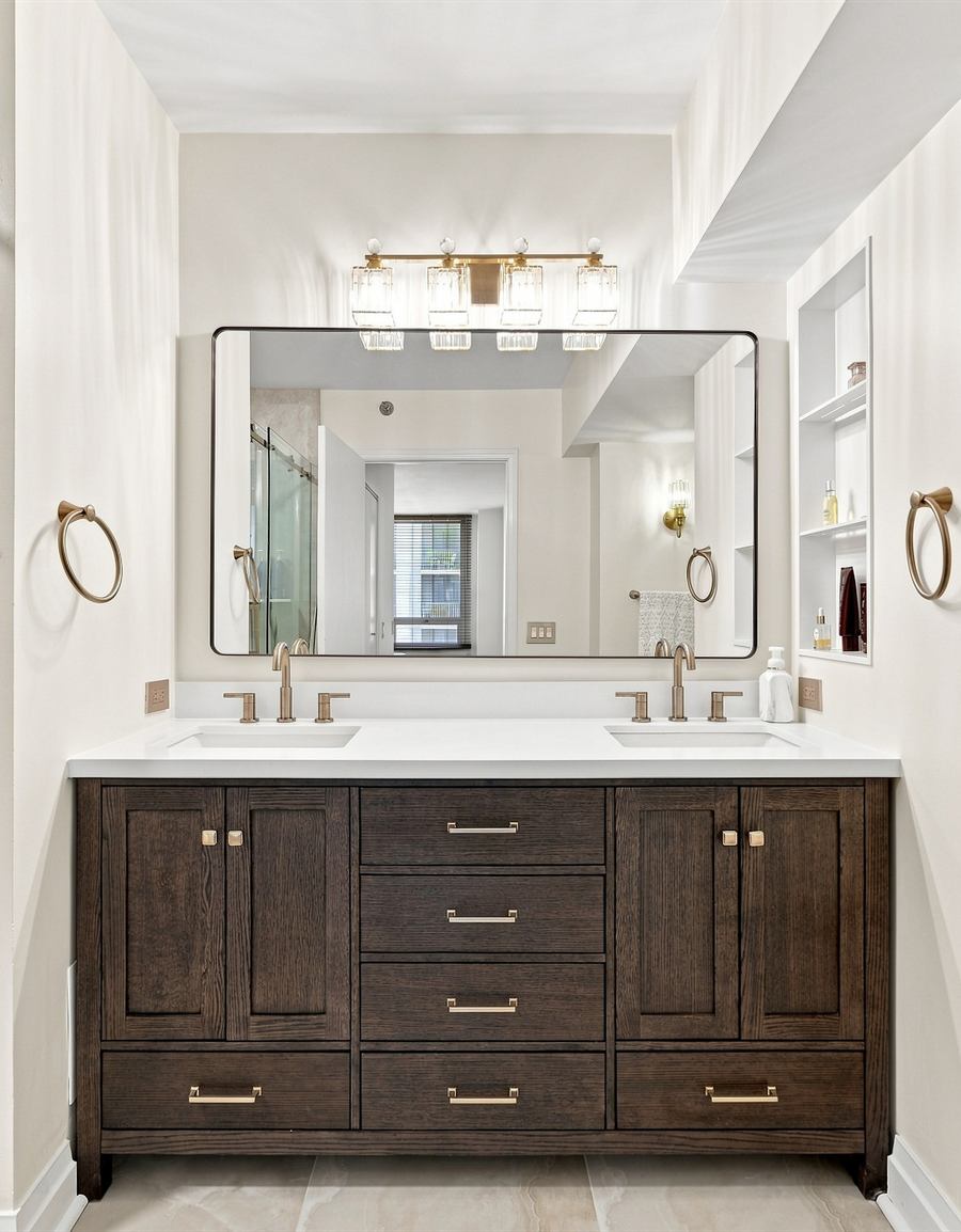 Walnut double vanity with unlacquered brass fixtures and a framed mirror