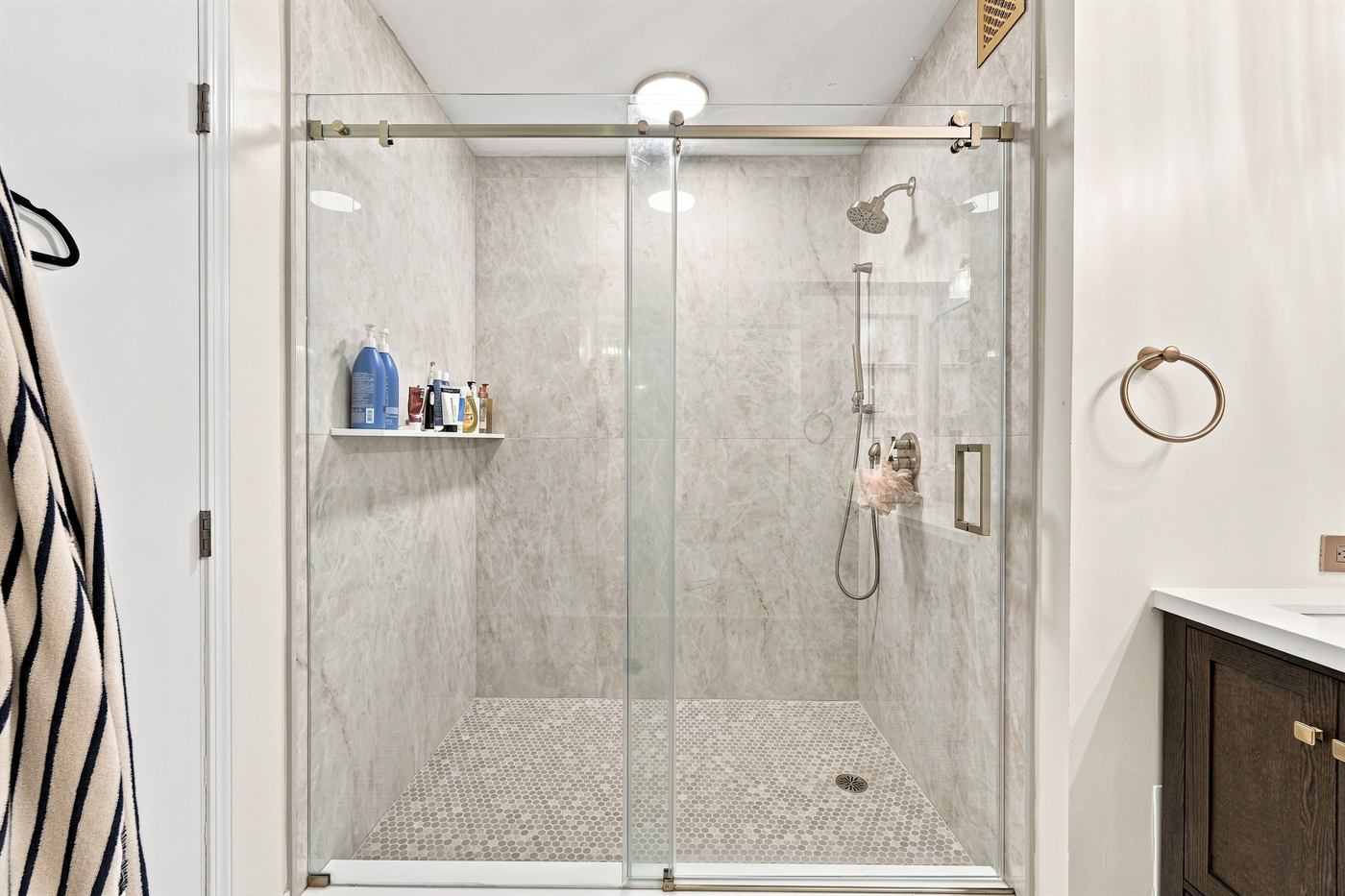 Marble-tiled walk-in shower with frameless glass and brass fittings