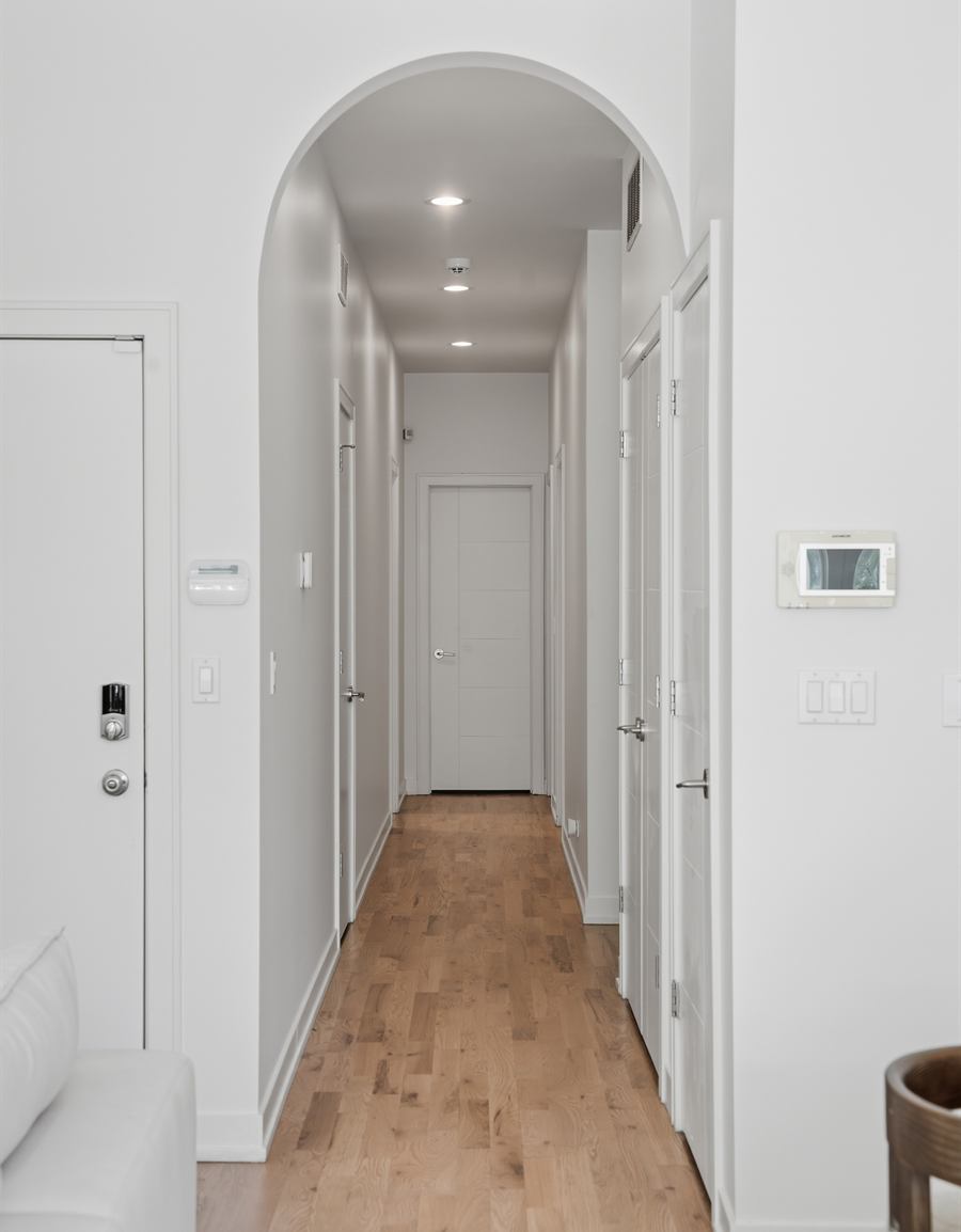 Arched plaster opening framing a hallway in white oak